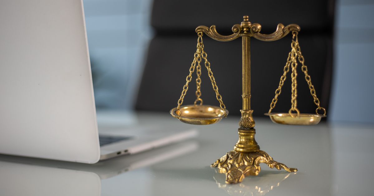 Balança da justiça sobre uma mesa ao lado de um laptop, ilustrando a legalidade de contratar um detetive particular