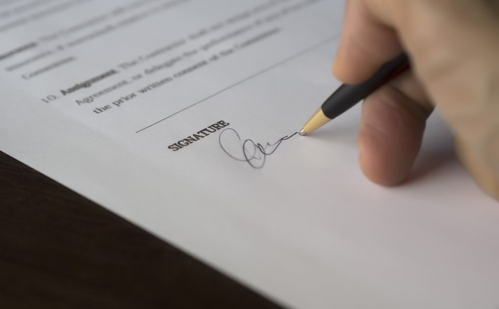 Mão assinando um contrato, ilustrando a segurança de contratar um detetive com serviço formalizado e sigiloso